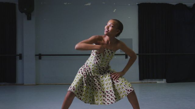 Woman elegantly moves in modern dance studio. African print dress adds cultural depth and vibrancy to her form. Image captures her passion and freedom. Use for promoting dance classes, celebrating diversity in arts, or as inspiring content for performance art features.