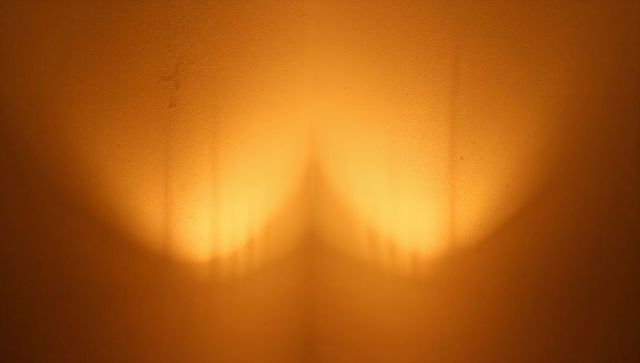 Casting warm amber halo on textured corner wall with symmetrical ribbed light bands