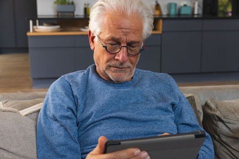 Senior Man Relaxing on Sofa and Using Tablet in Cozy Lounge