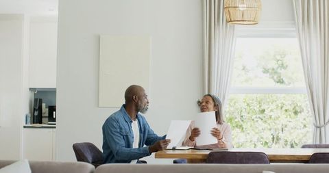 Couple reviewing documents at sunlit dining table planning finances and home decisions