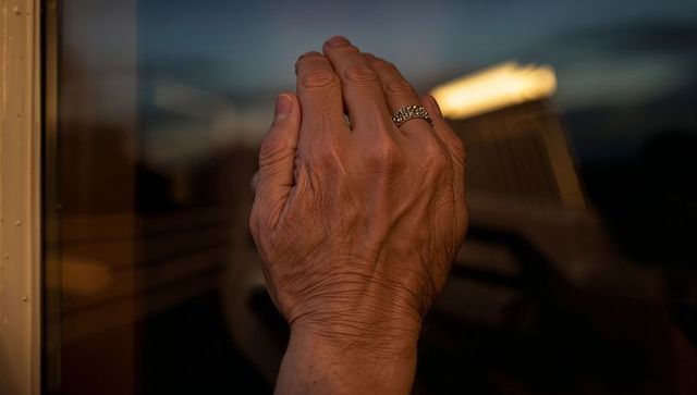 Senior Hand Pressing Window at Dusk with Reflective Ring, Wrinkled Veins and Emotion
