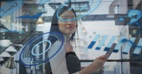 Professional woman interacting with futuristic HUD on glass holding tablet in modern office environm