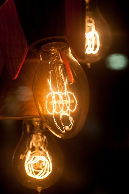 Closeup showing glowing filaments inside vintage Edison-style light bulbs, reflecting retro and minimalist decor. Ideal for themes such as interior design, cozy settings, energy efficiency, and warm lighting.