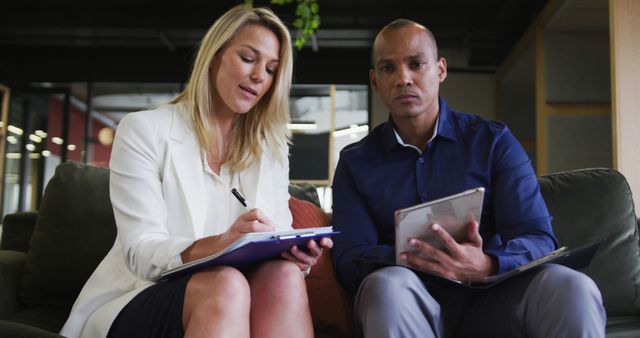 Business professionals collaborating on documents in office lounge - Download Free Stock Images Pikwizard.com