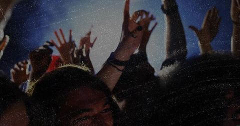 Energetic concert crowd raising hands in blue haze with backlit silhouettes, nightlife vibe