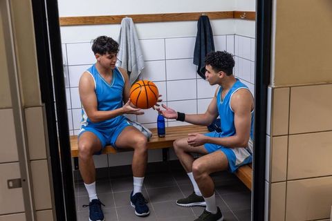 Teammates Bond While Passing Basketball in Locker Room
