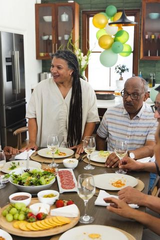 African american couple celebrating in kitchen, sharing meal with charcuterie and wine
