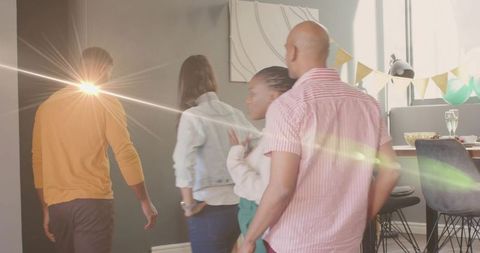 Friends walking into bright living room with party bunting and teal balloons