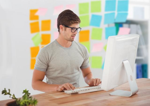 Handsome man in spectacles using desktop pc