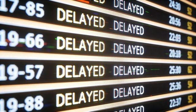 Airport departure board displaying multiple delayed statuses on led panel