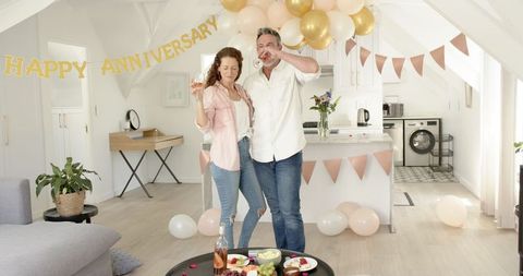 Mature Couple Celebrating Anniversary with Wine and Snacks at Home
