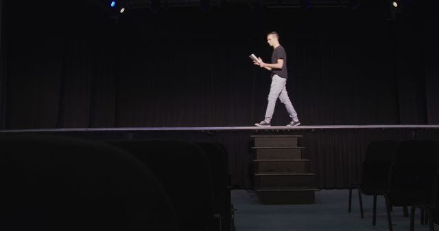 Young Man Rehearsing with Script on Dark Theater Stage - Download Free Stock Images Pikwizard.com