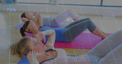 Women Performing Crunches in Group Fitness Class on Colorful Mats with Digital Overlay