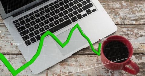 Displaying laptop and coffee with green financial chart overlay on rustic desk