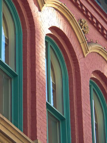 Vintage brick building facade with green trims design and arched windows