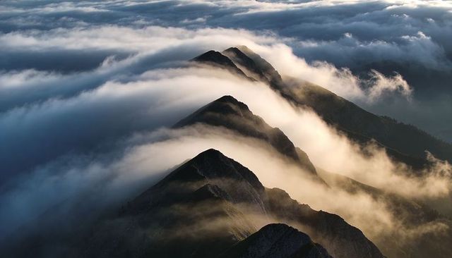 Sunlight Revealing Serrated Alpine Ridge Through Rolling Sea of Clouds