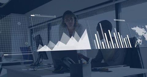 Two women reviewing analytics dashboard at modern office workstation with data overlay