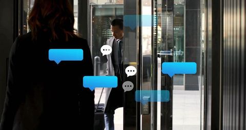 Asian businessman walking through glass revolving doors with digital chat bubbles overlay