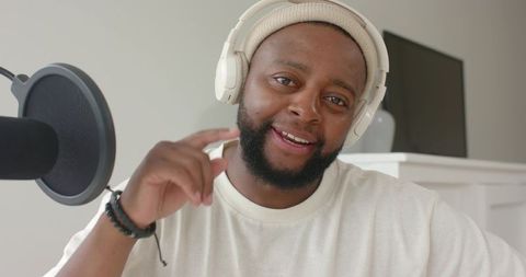 African american podcaster speaking and gesturing near microphone wearing headphones