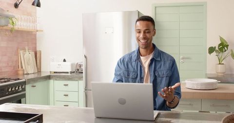 Smiling man video conferencing in modern kitchen workspace