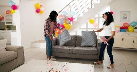 Friends Cleaning Up Living Room After Festive Celebration