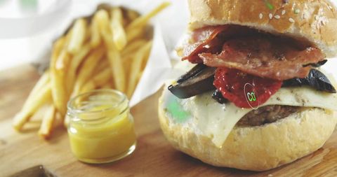 Gourmet bacon cheeseburger with mushrooms and melted cheese on rustic bun with fries