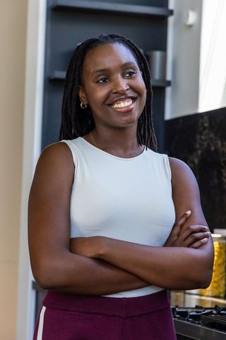 Confident african american woman standing arms crossed in modern minimalist kitchen