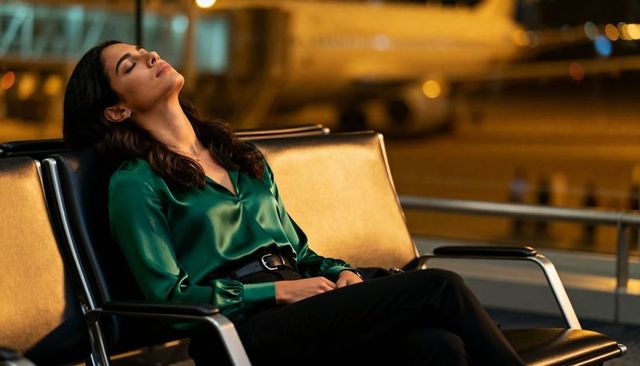 Business traveler resting during overnight airport layover wearing satin green blouse