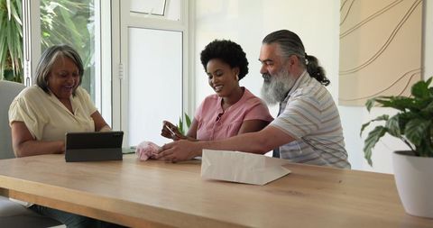 Senior Couple Enjoy Online Shopping at Home with Young Assistant