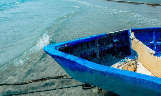 Weathered Blue Boat Ashore on Calm Beach Waters - Download Free Stock Images Pikwizard.com