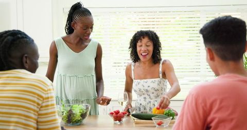 Diverse Friends Cooking and Mixing Fresh Green Salad Together