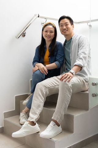 Couple sitting on modern stair landing smiling in bright minimalist interior with sneakers