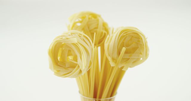 Image displays an assortment of uncooked Italian pasta, including tagliatelle and spaghetti, arranged aesthetically against a white backdrop. Ideal for use in cooking blogs, recipe websites, culinary magazines, or Italian restaurant promotions.