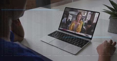 Man watching woman in yellow cardigan on laptop with code overlay suggesting remote work and cyberse