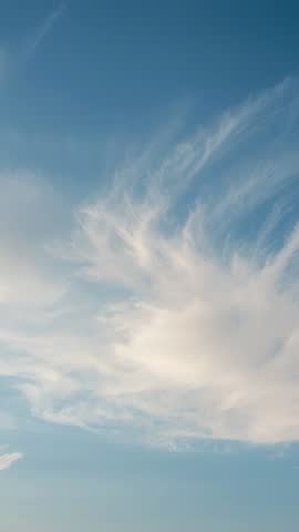 Vertical video of wispy cirrus clouds drifting across calm azure sky, high-altitude motion
