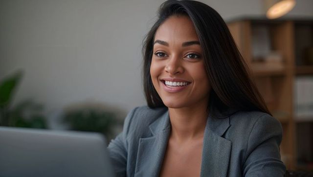 Smiling businesswoman working at laptop corporate headshot in modern office workspace for leadership