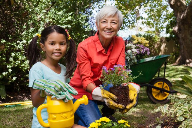 Portrait of smiling girl and grandmother gardening in backyard