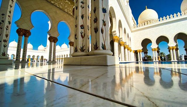 Framing marble columns reflecting on polished courtyard floor with floral inlay arches