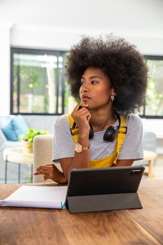 Focused Woman Contemplating Work at Home with Tablet