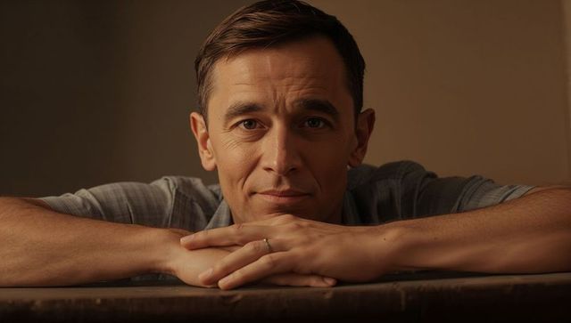 Introspective man leaning on wooden table wearing ring intimate warm moody headshot closeup
