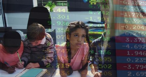 Young students collaborating and writing in classroom with stock market data overlay