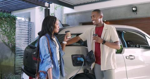 Couple enjoying coffee while charging electric car at home