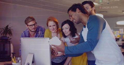 Team collaborating around desktop and tablet in bright open-plan office brainstorming ideas