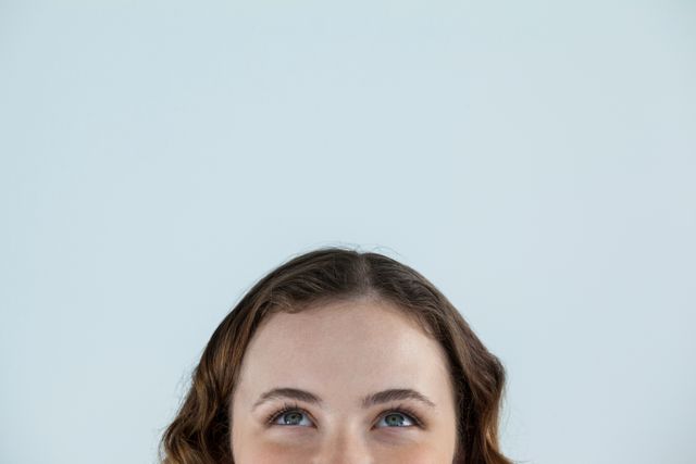 Close-up of beautiful woman looking upward against grey background