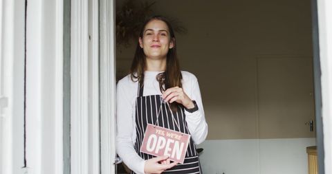 Friendly waitress holding open sign at local cafe entrance