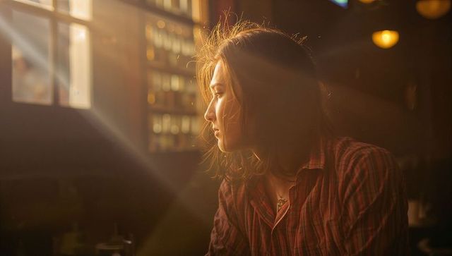 Woman Gazing by Window in Cozy Cafe with Warm Lighting