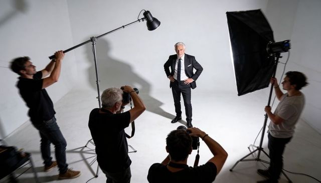 Senior executive posing in studio with photography crew and dramatic studio lighting