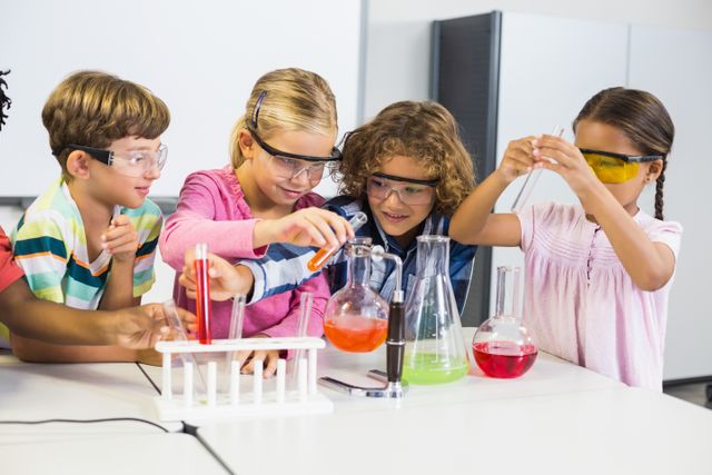 Group of children wearing safety goggles conducting a science experiment in a school laboratory. They are using beakers and test tubes with colorful liquids, demonstrating teamwork and curiosity. Ideal for educational content, STEM programs, school brochures, and science-related articles.
