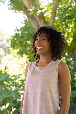 African american woman smiling outdoors in park wearing pink tank top sunny portrait