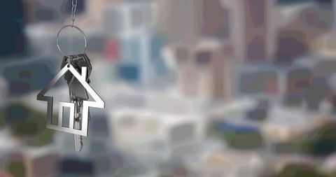 Silver house key and fob against blurred urban cityscape